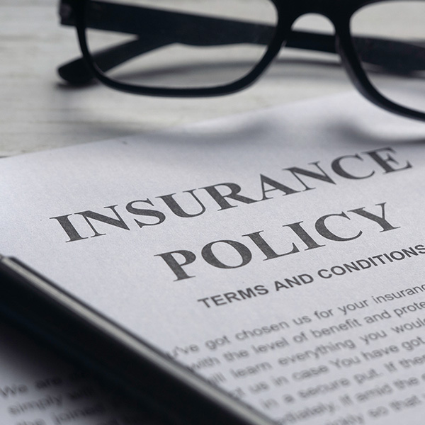 Glasses and Insurance Policy letter on a white wooden table